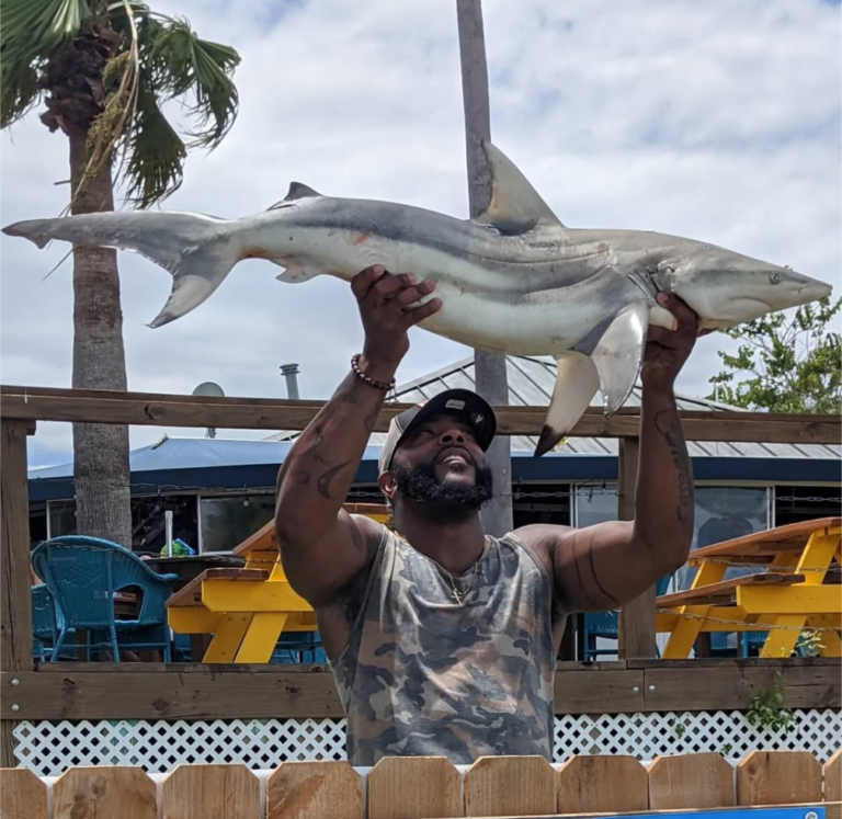 Angler holding up a shark caught on a shark fishing charter