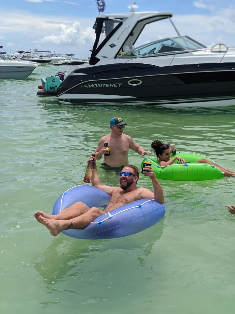 Guests floating on an inner tube beside the boat at a sandbar