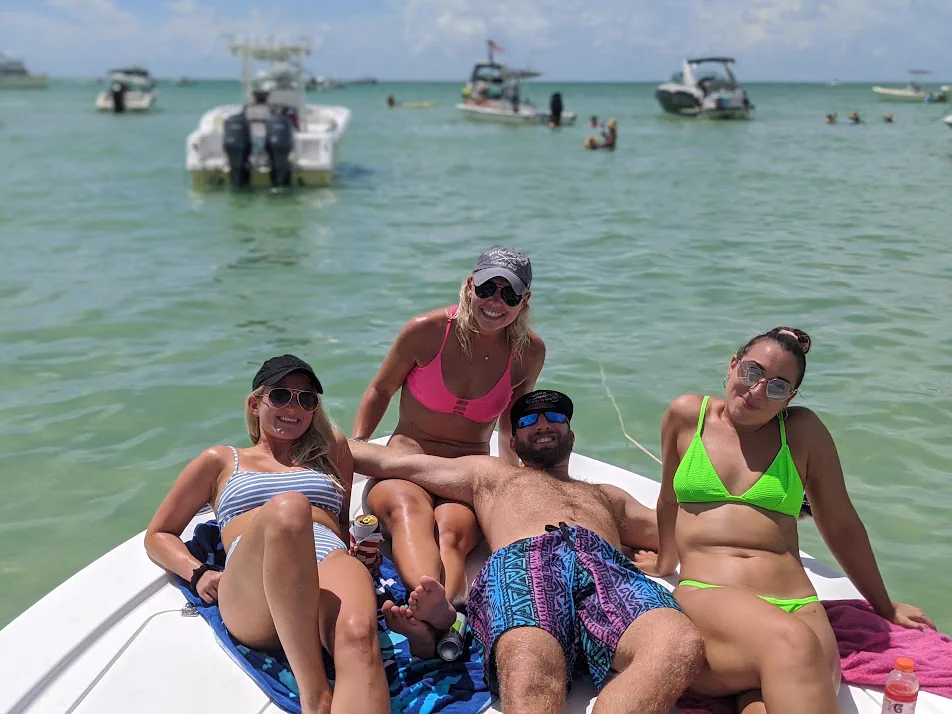 Friends relaxing on the bow of the boat at a sandbar on an island hopping cruise