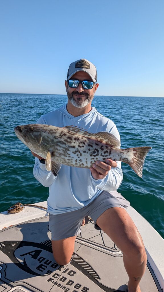 Angler holding a gag grouper on the deck after a nearshore charter