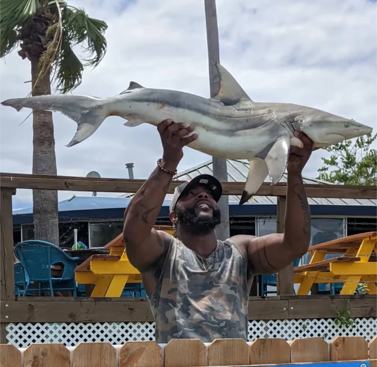 Angler holding up a shark caught on a shark fishing charter