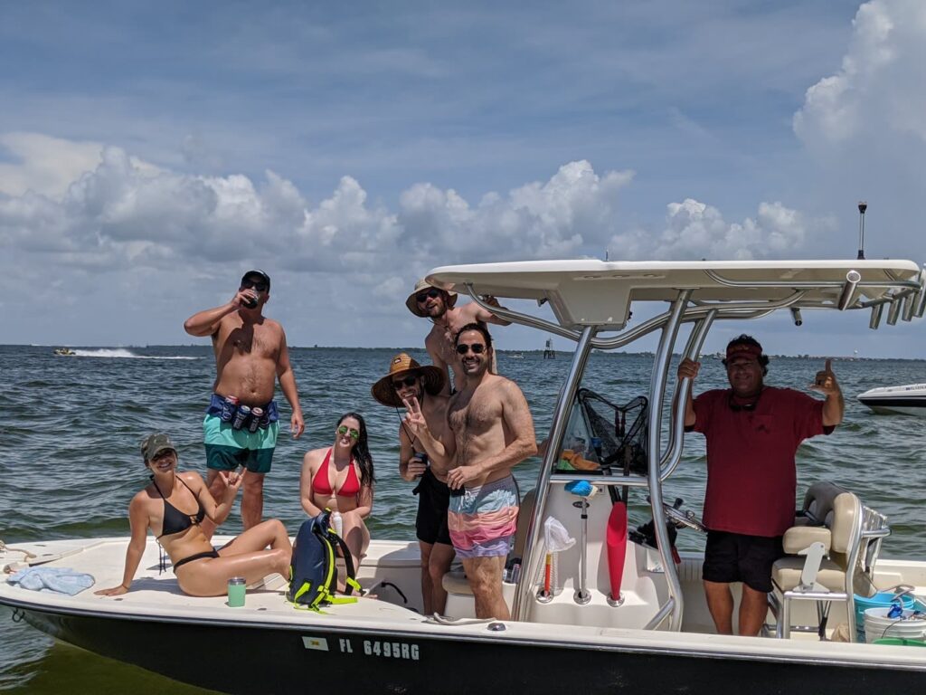 A group of friends with drinks on the boat anchored at a Tampa Bay sandbar