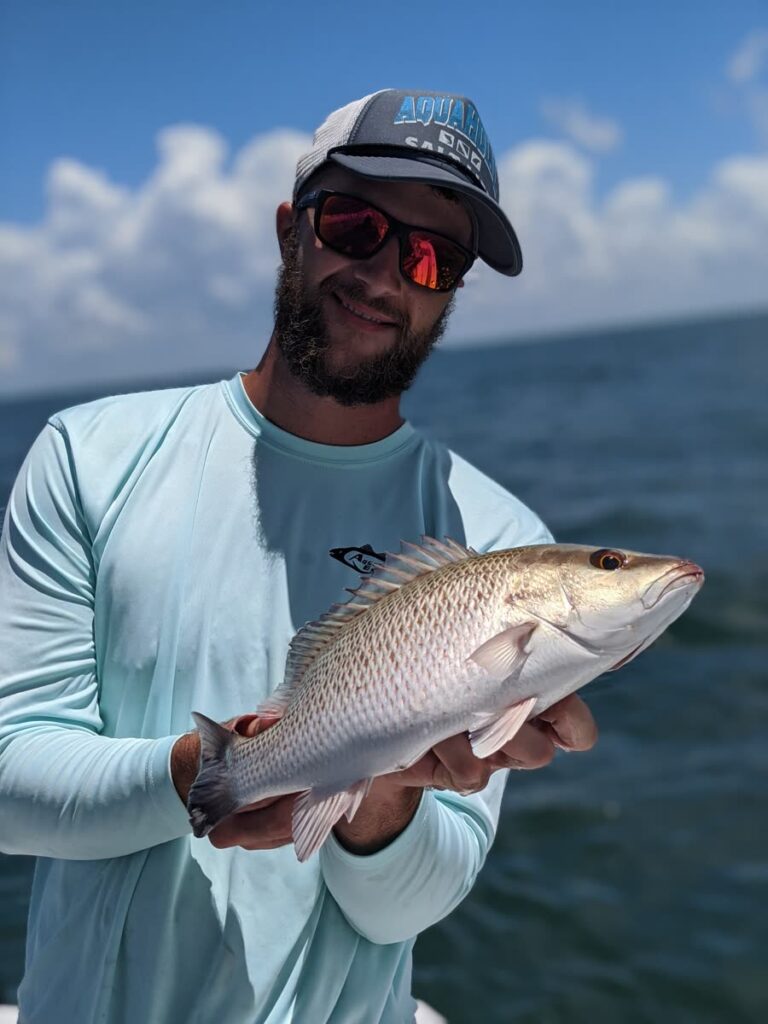 Angler holding a mangrove snapper caught on a Tampa fishing charter