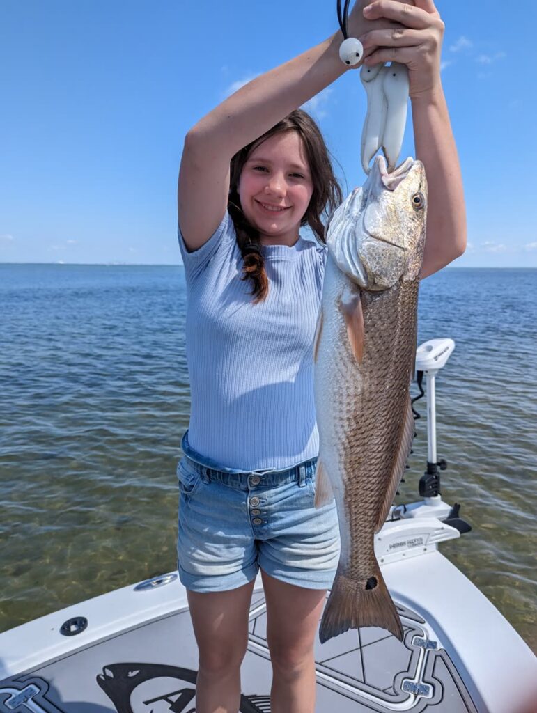 Young angler holding up a redfish on an inshore fishing charter in Tampa Bay