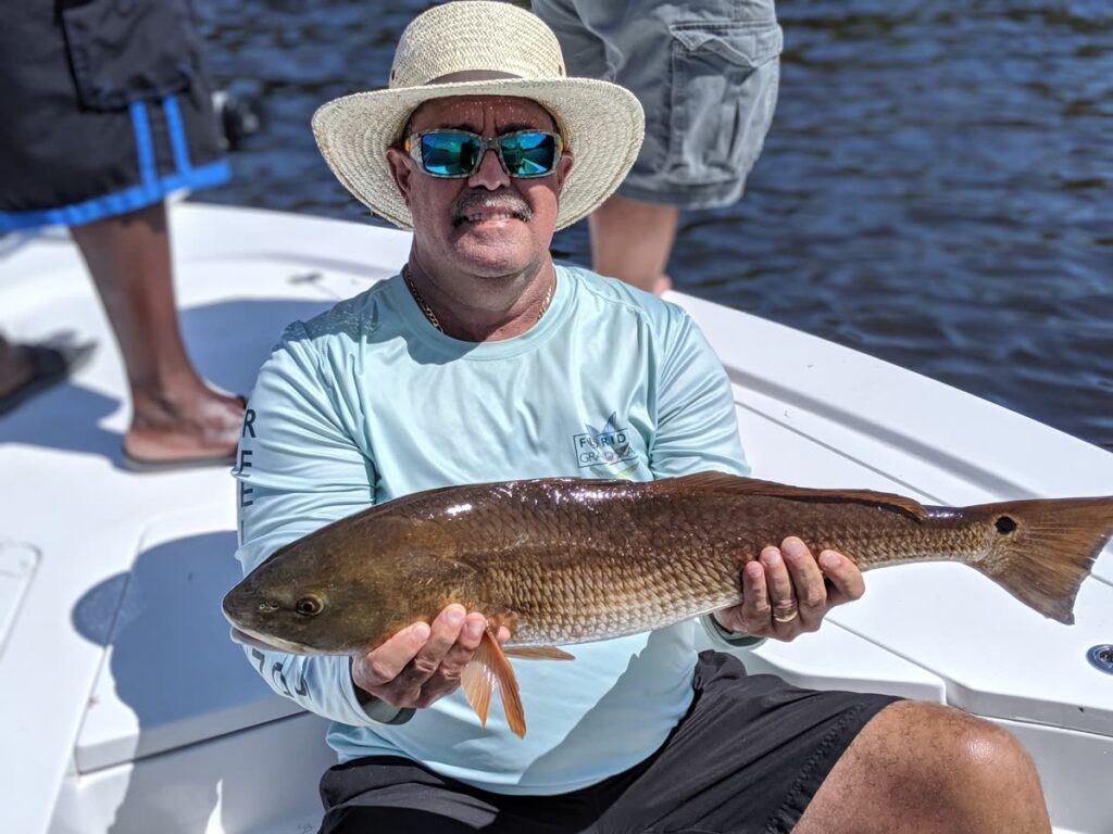 Angler on the bow holding a redfish caught on a September Tampa Bay fishing charter