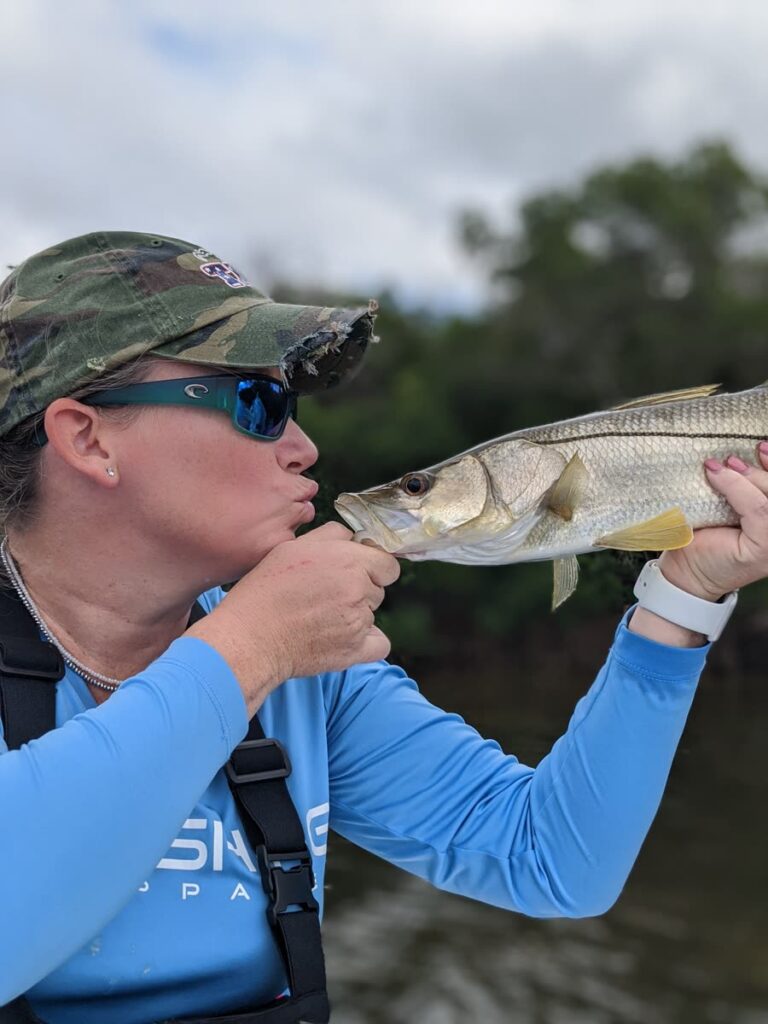 Angler kissing a snook before releasing it on a December Tampa Bay charter