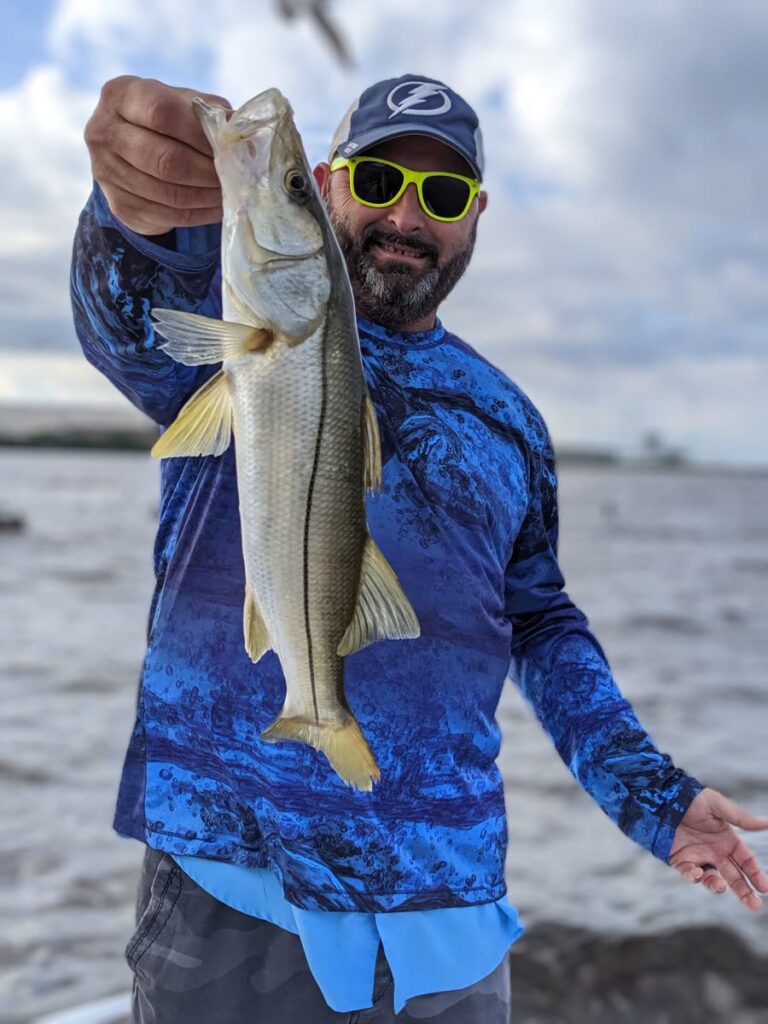 Angler holding a snook caught on a Tampa fishing charter in November