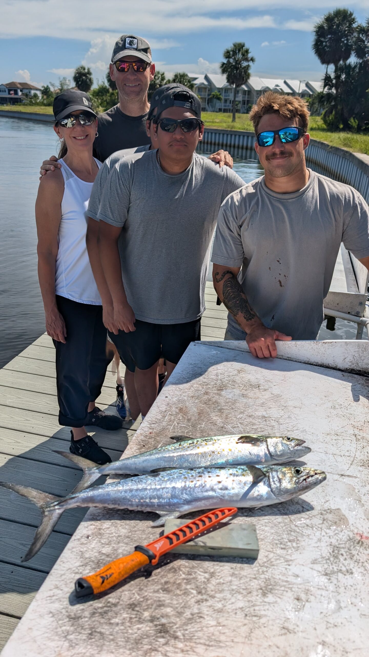 Four guests at the dock with two Spanish mackerel on the fillet table after a Tampa Bay charter